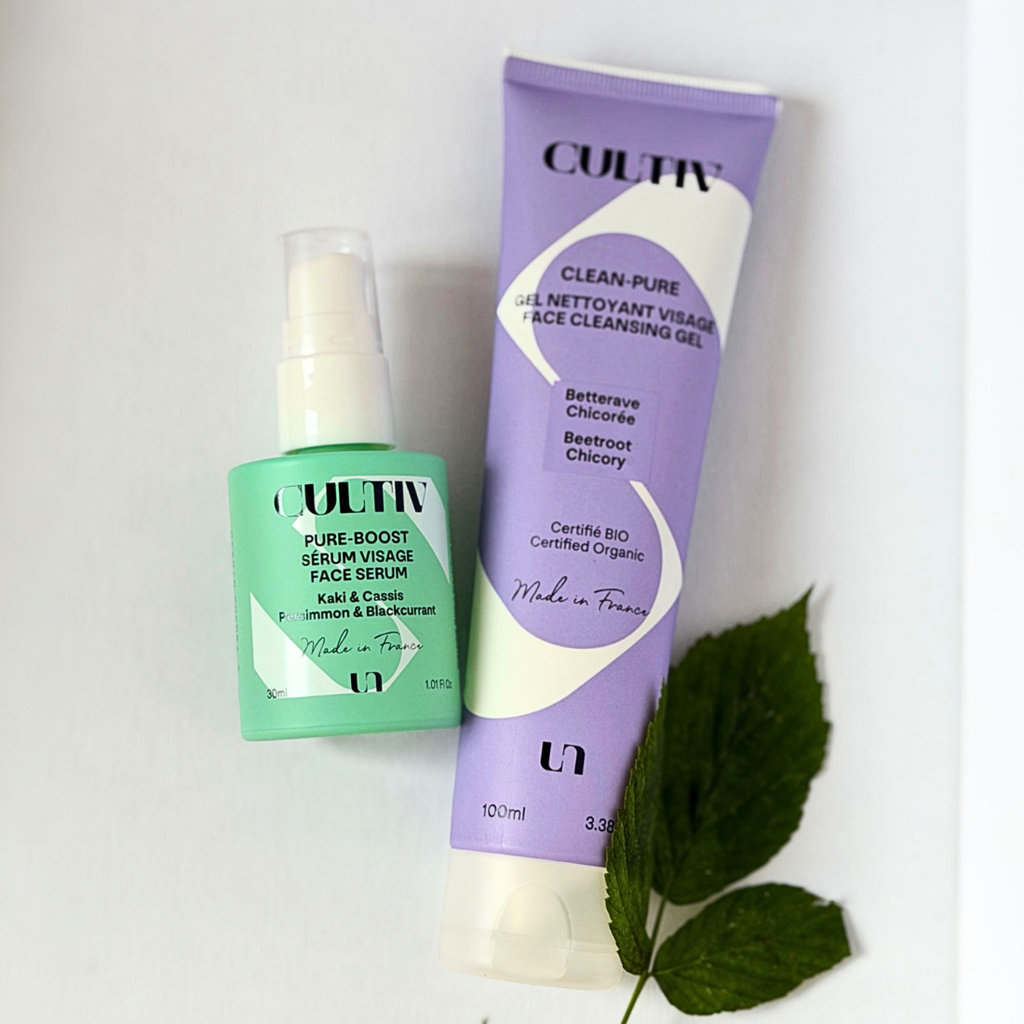 Two CULTIV skincare products arranged on a white background: a mint green bottle of Pure Boost Serum and a lavender tube of Clean Pure Face Cleansing Gel, with green leaves as styling props.