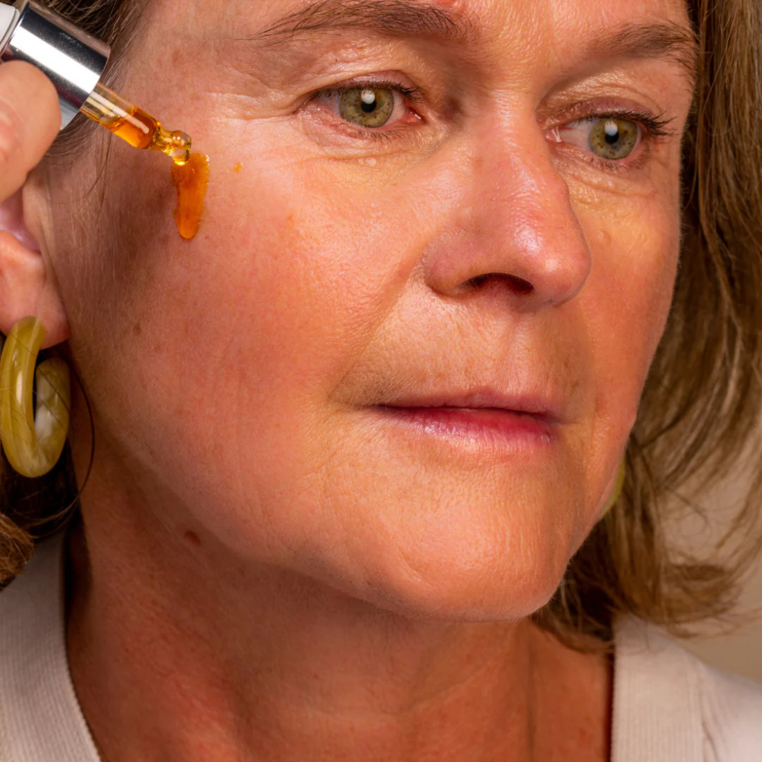 Woman applying a dropper of Oden_vitaminoil to her face