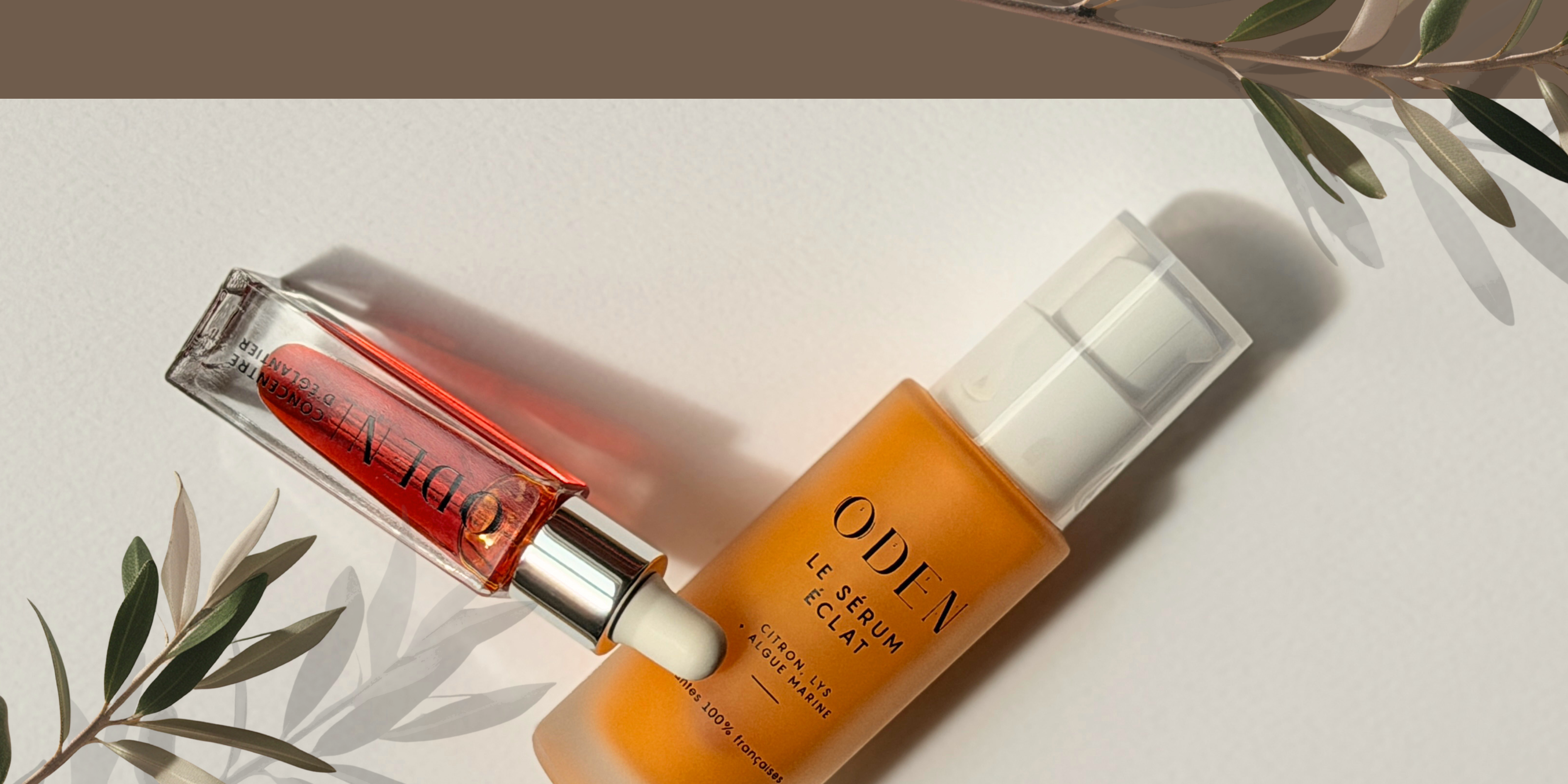 Two skincare products, a serum and a bottle, on a light background with leaves.